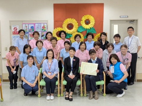 東大泉デイサービスお客様作成のひまわり壁画の前で
