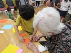 7月の保育園交流会の様子です。園児と一緒に折り紙でコマを作りました。